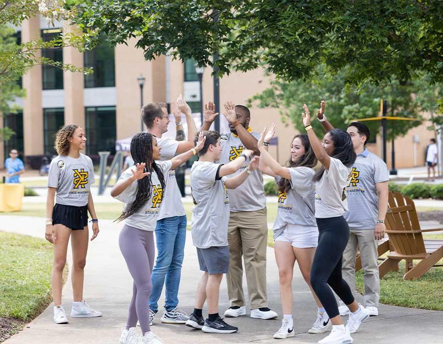 group of ksu first fight students high fiving each other outside.